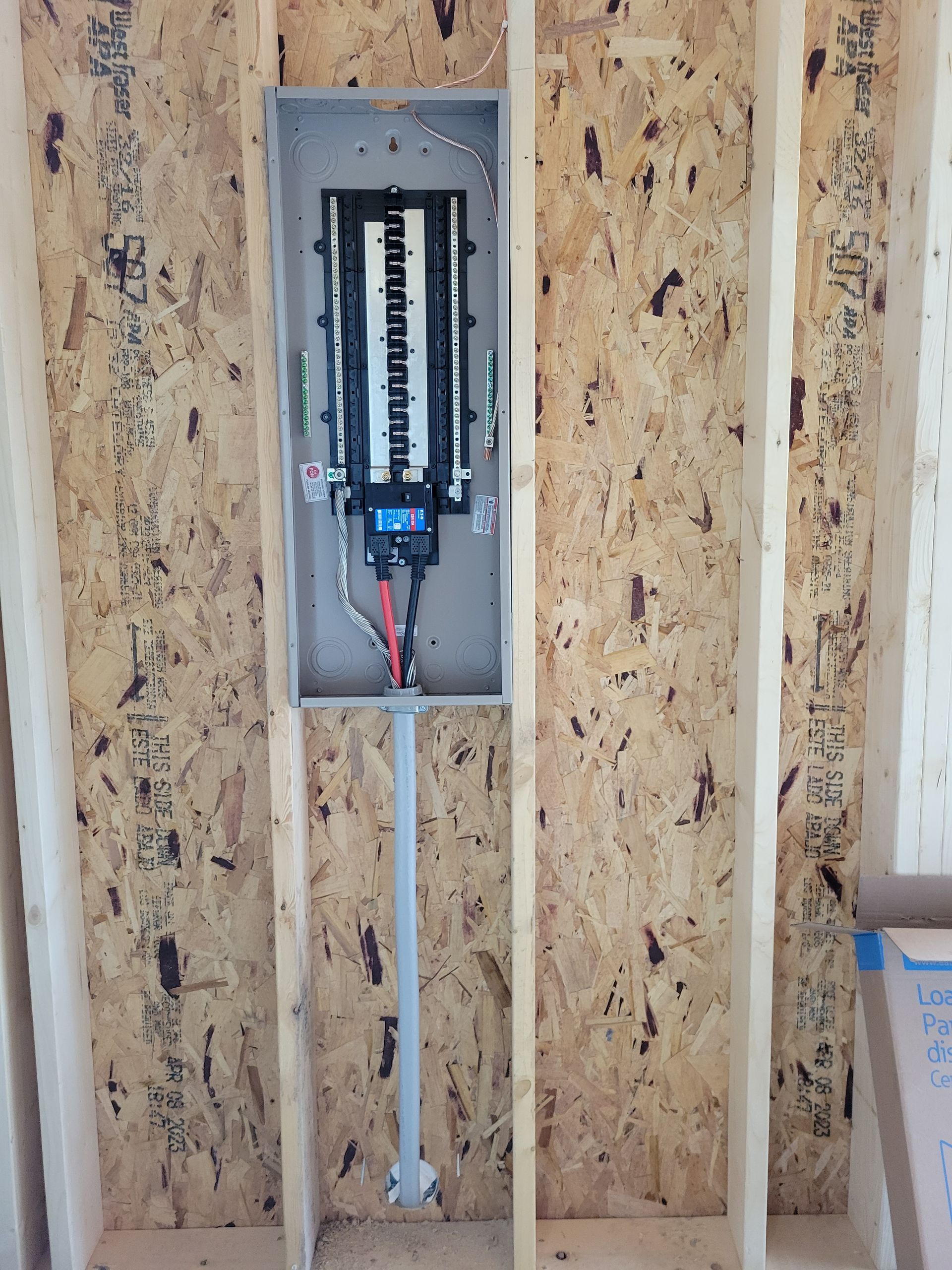 Electrician working on electrical panel, wearing safety glasses, inside a home.