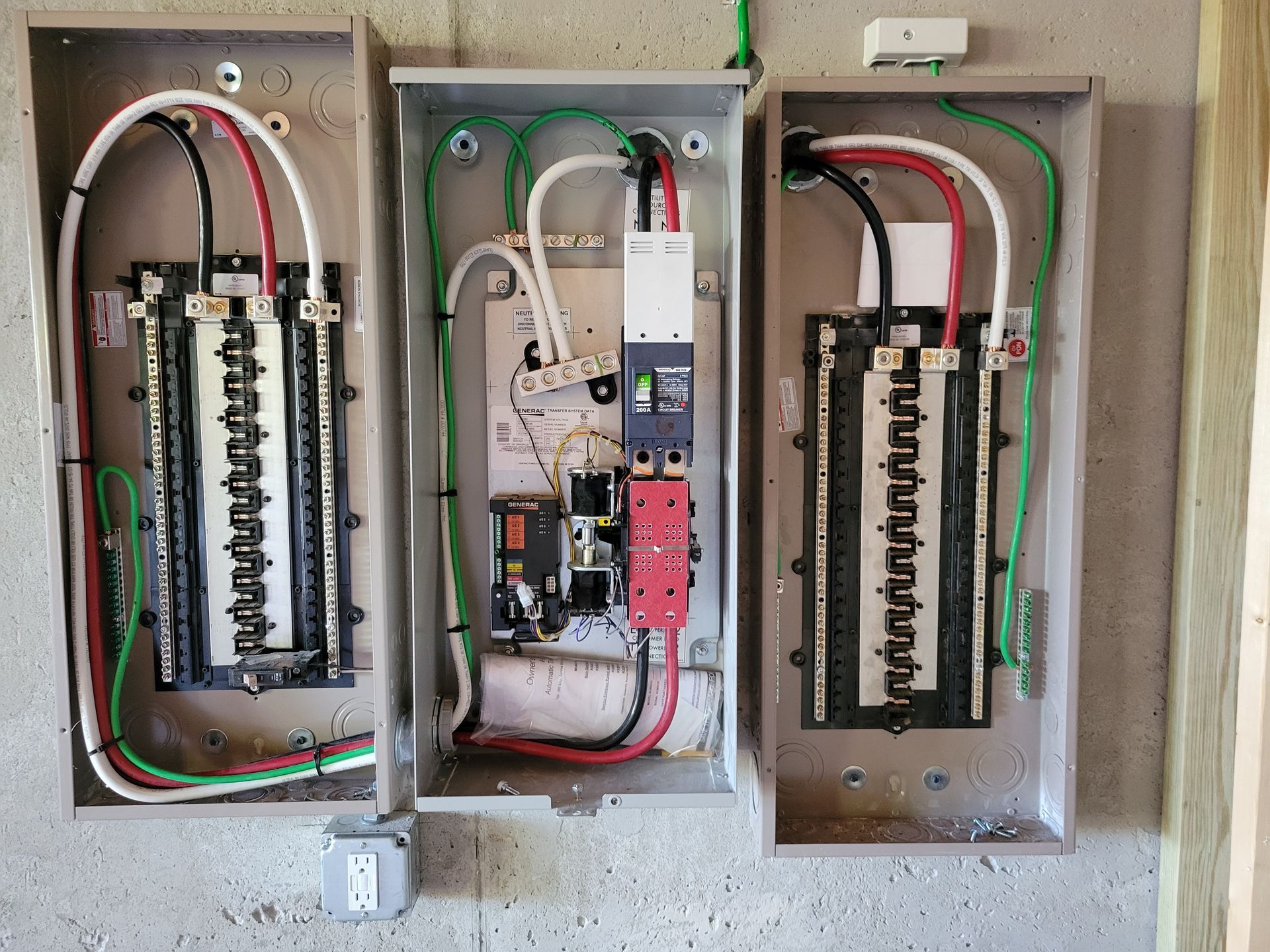 Gray electrical panel with colored wires and circuit breakers mounted on a wall.