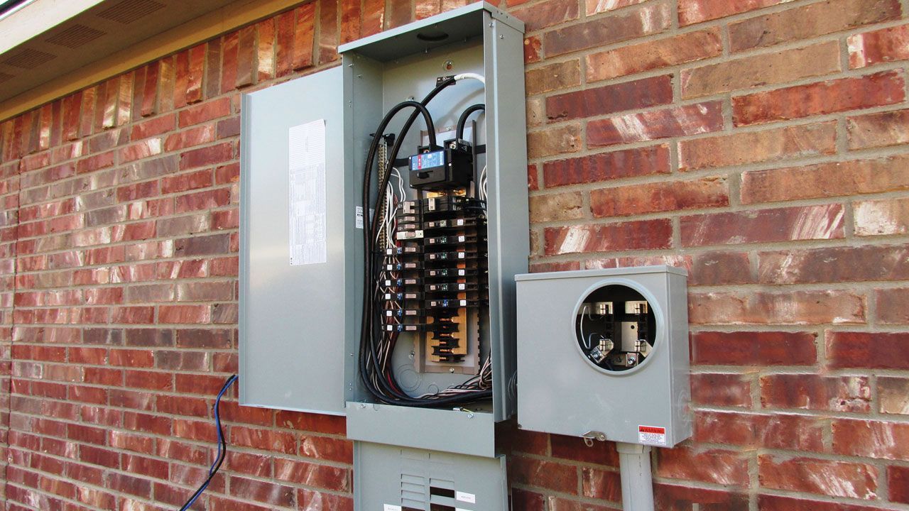 Electrician in a yellow safety vest working on an electrical panel in an office.