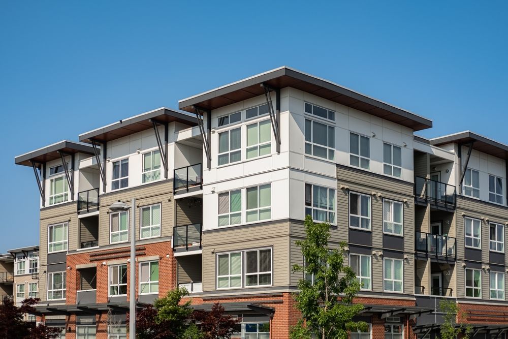 Multi-story apartment building with balconies, various colors, and clear blue sky.