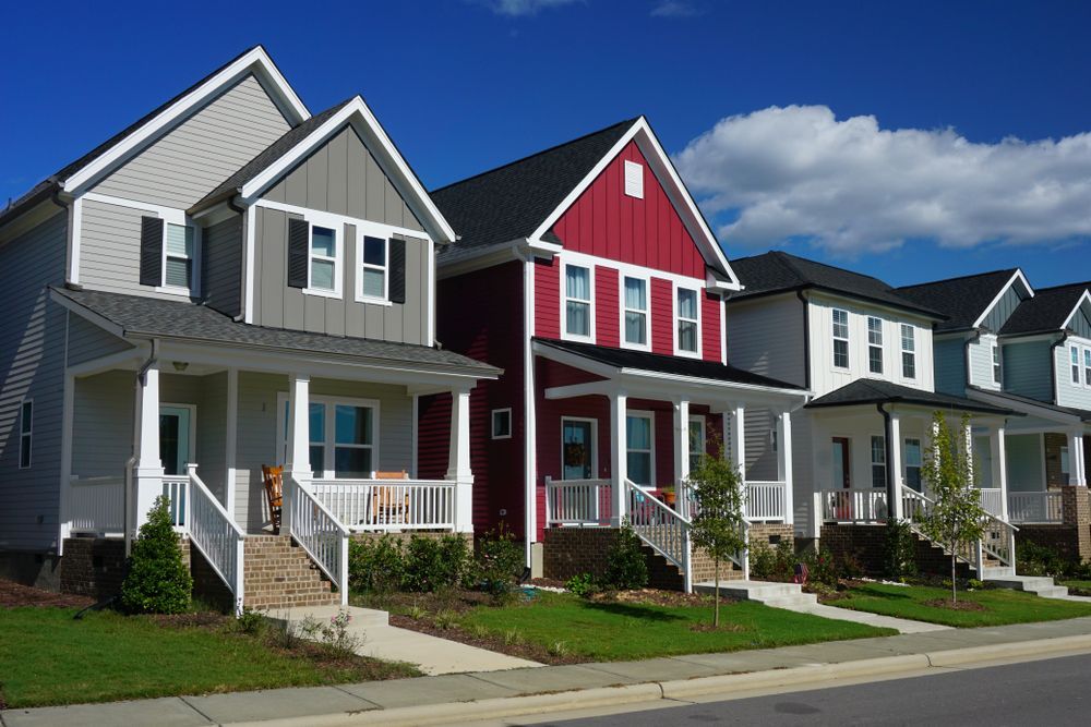 Row of colorful two-story houses with front porches under a blue sky.