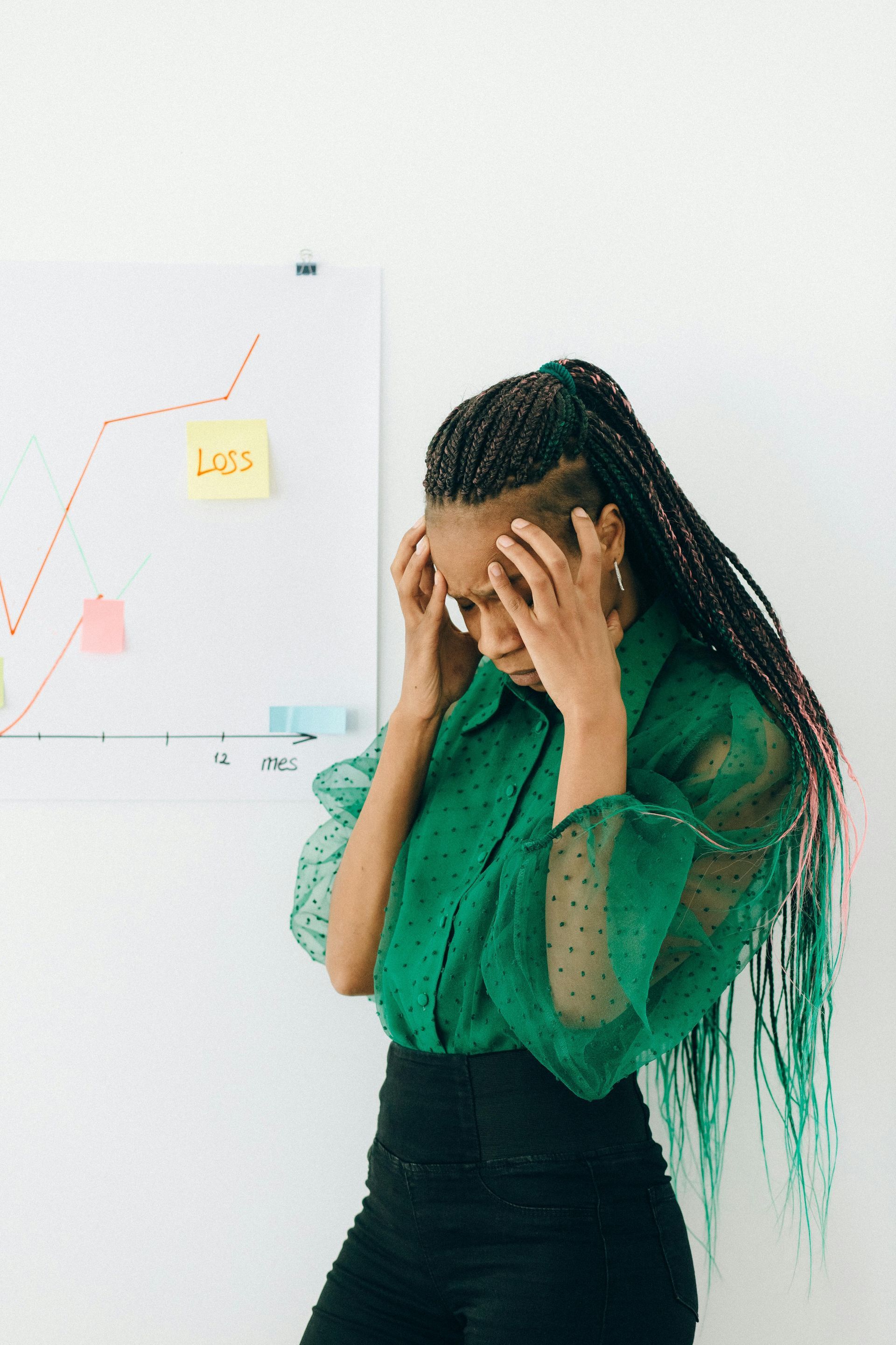 A woman in a green shirt is standing in front of a whiteboard with a graph on it.