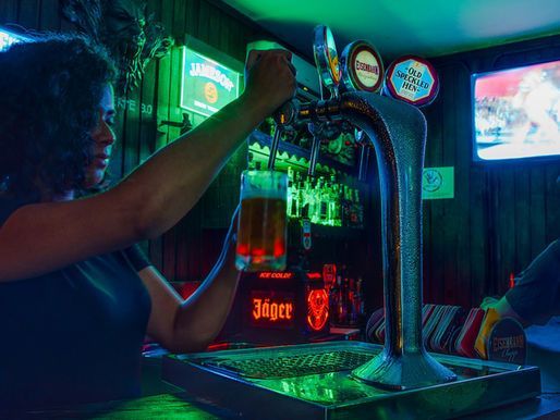 A woman is pouring beer into a glass at a bar.