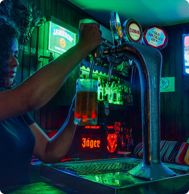 A woman is pouring beer from a tap that says jager on it