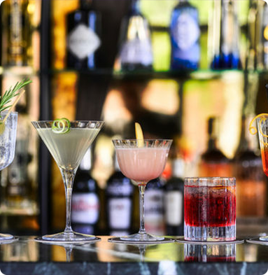 A variety of cocktails are sitting on a bar counter.