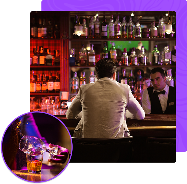 A man is sitting at a bar with a glass of beer in front of him.