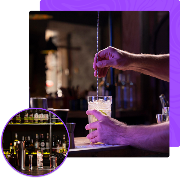 A person is stirring a drink in a glass with a straw.