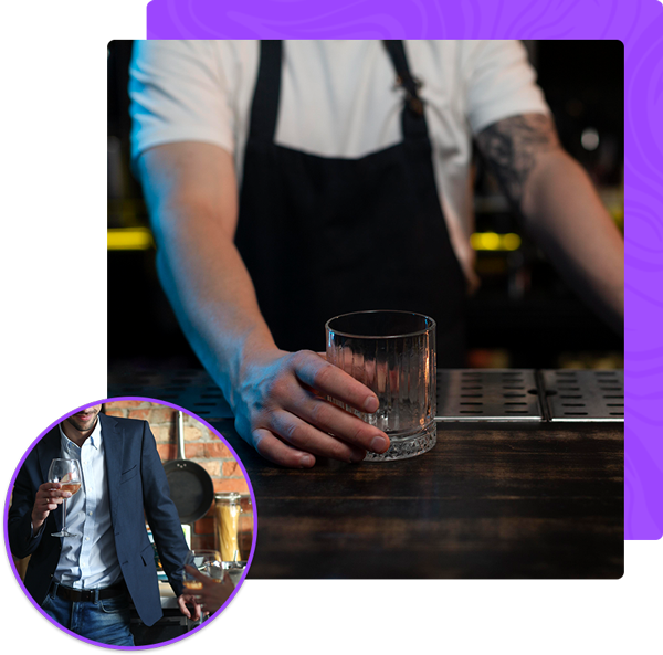 A bartender is holding a glass of whiskey at a bar