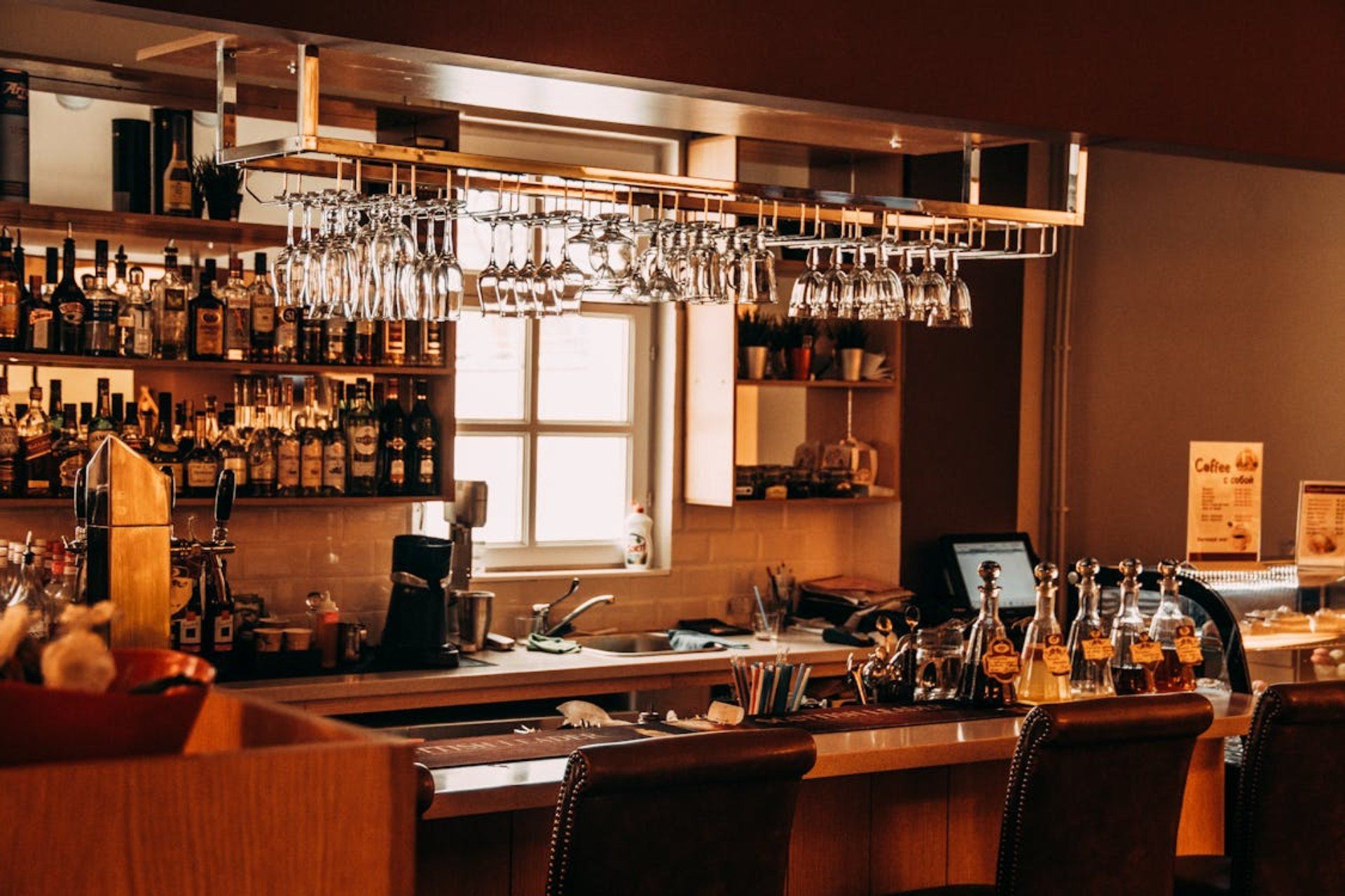 A row of bottles of liquor are lined up on a shelf in a bar.