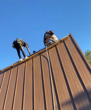 Two men are working on a metal roof with the words metal roofing below them