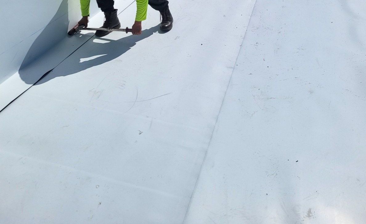 Two men are working on a white roof.