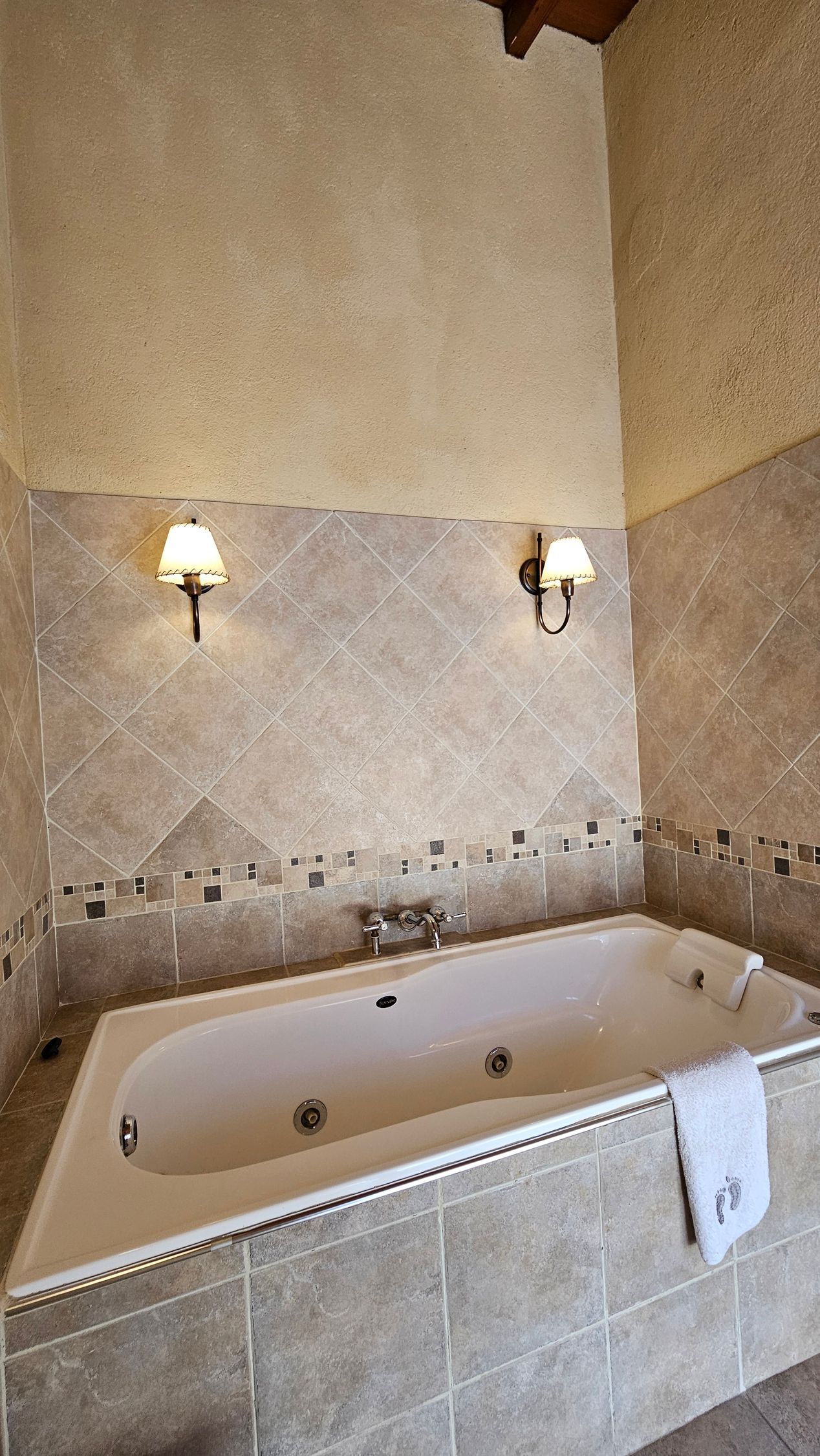Whirlpool bathtub in a tiled alcove, two sconces on the wall.