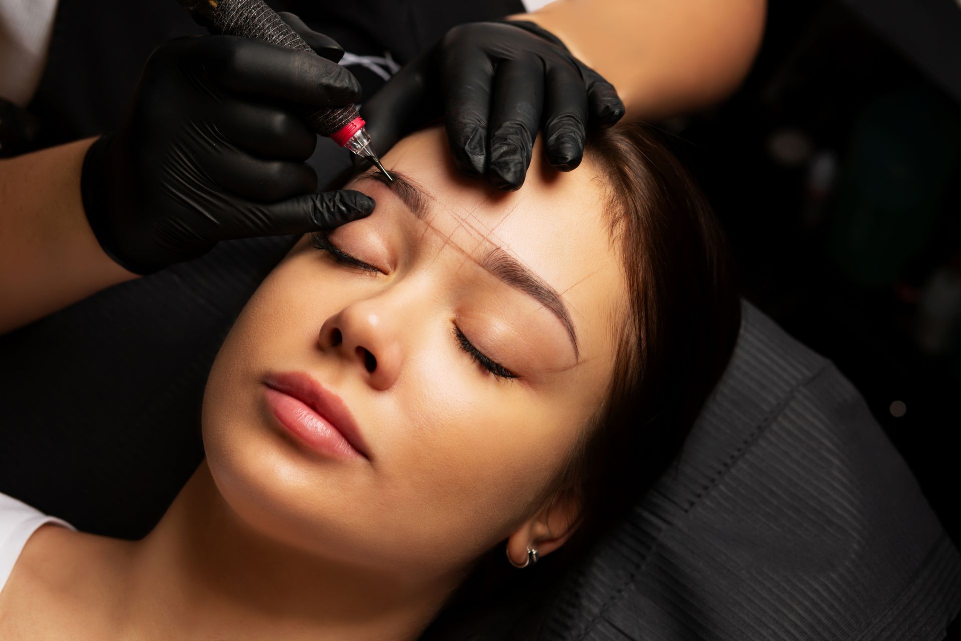 A woman is getting a tattoo on her eyebrows.