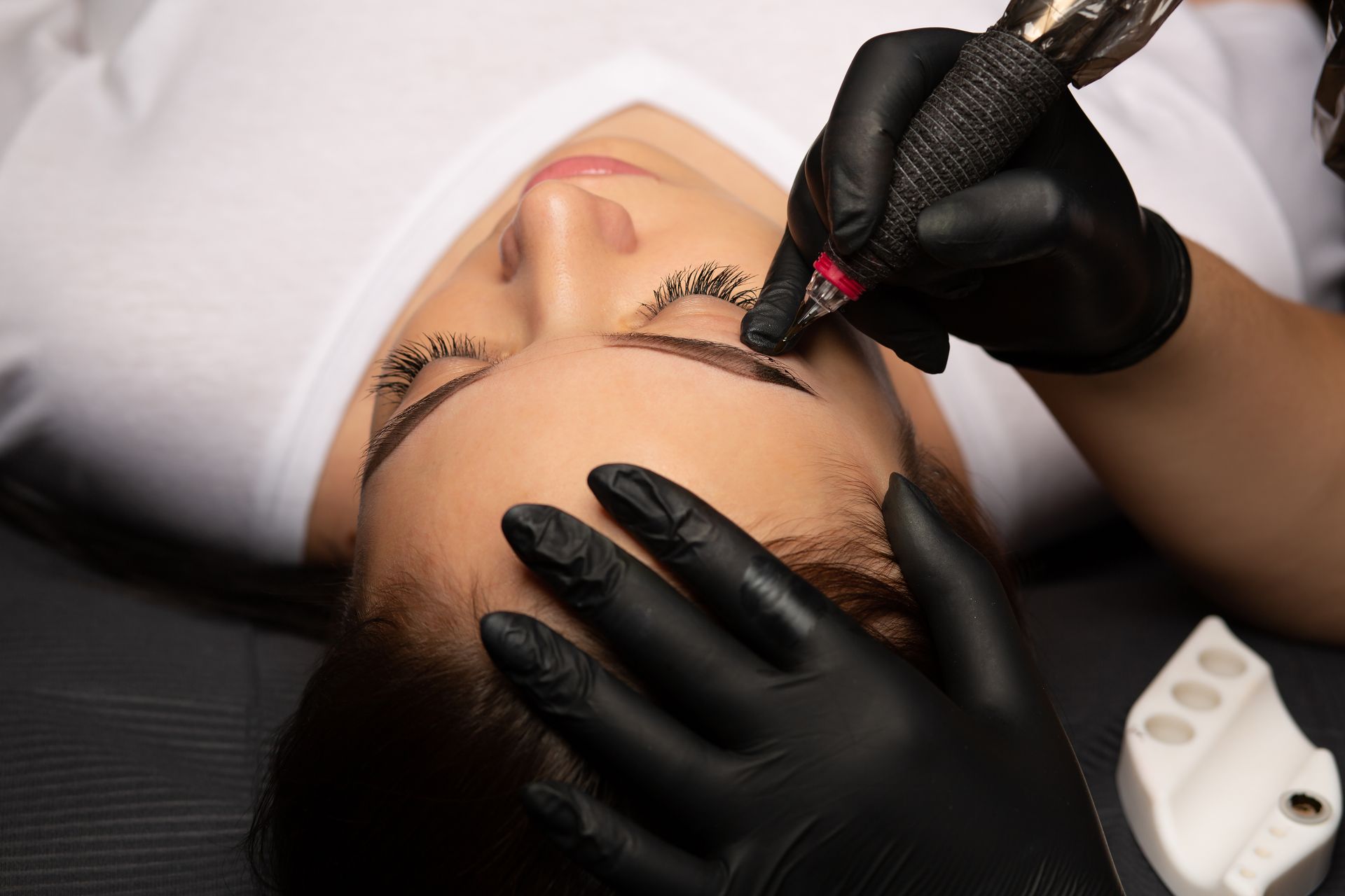 A woman is getting permanent makeup on her eyebrows.