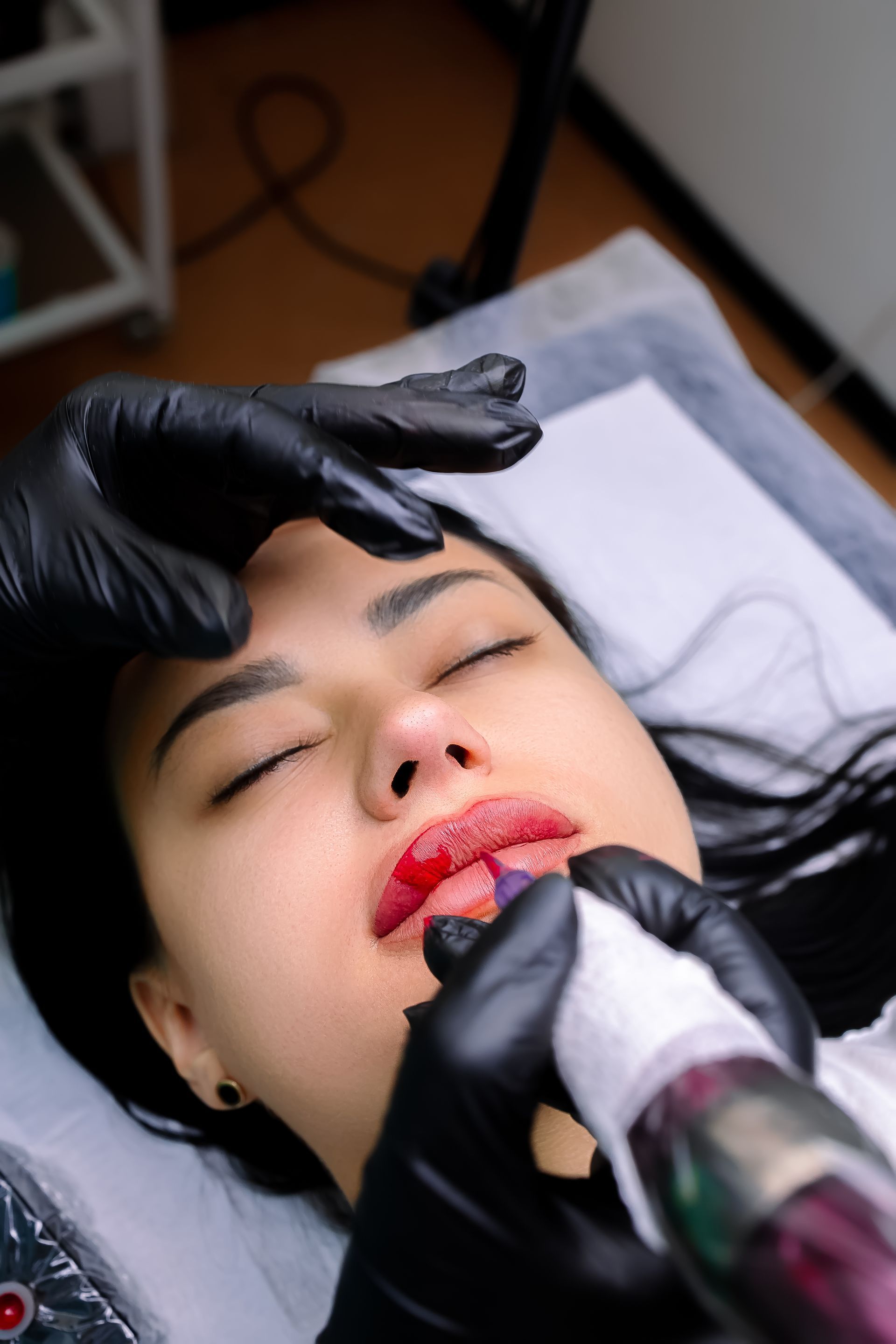 A woman with red lips is getting a lip blushing.