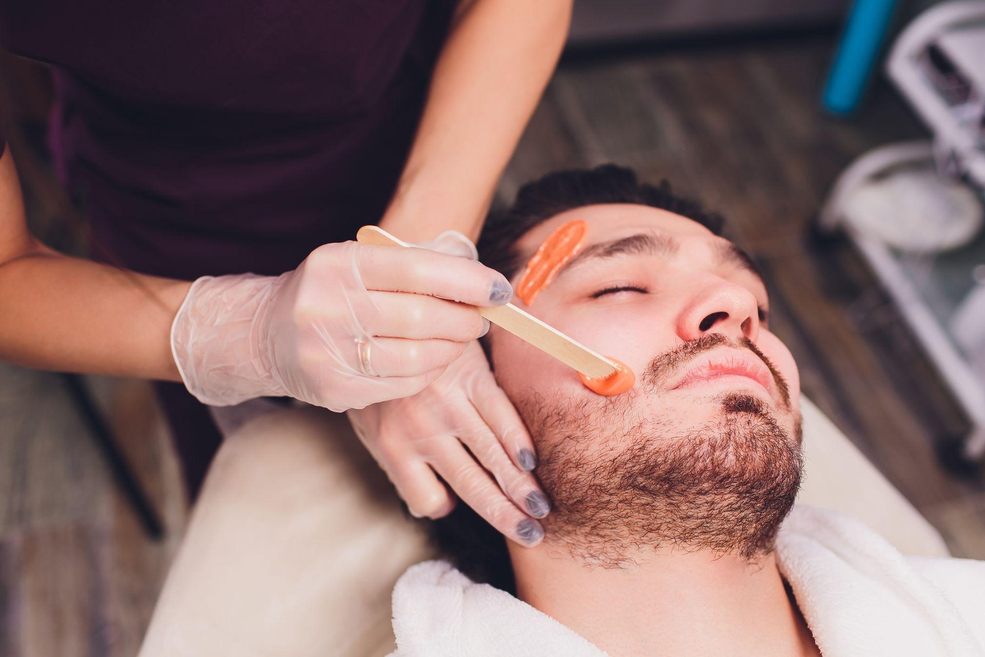 A man is getting his beard waxed in a beauty salon.