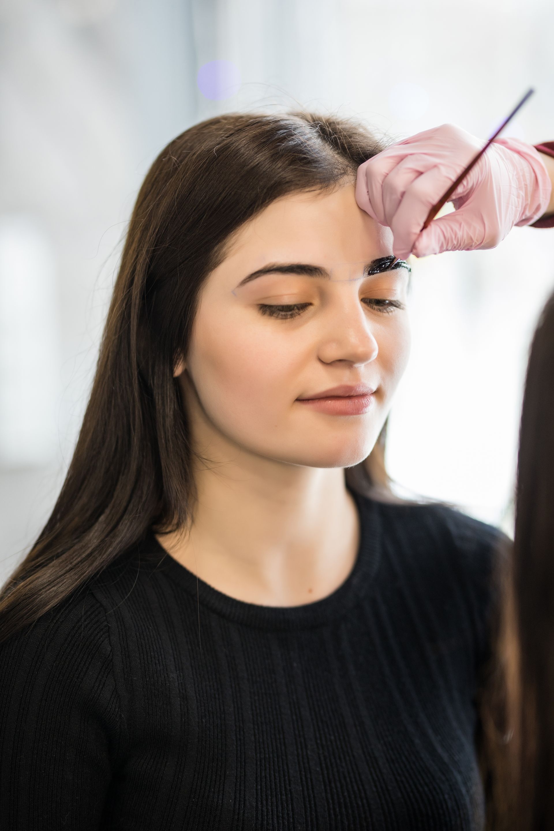 A woman is getting her eyebrows painted in a beauty salon.