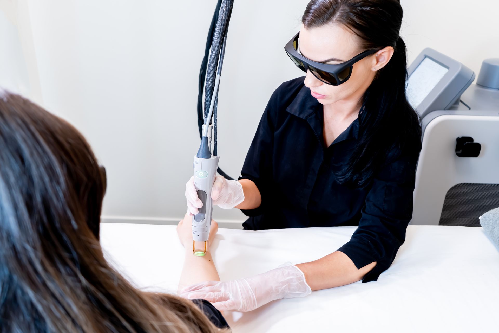 A woman is getting a laser hair removal treatment on her arm.