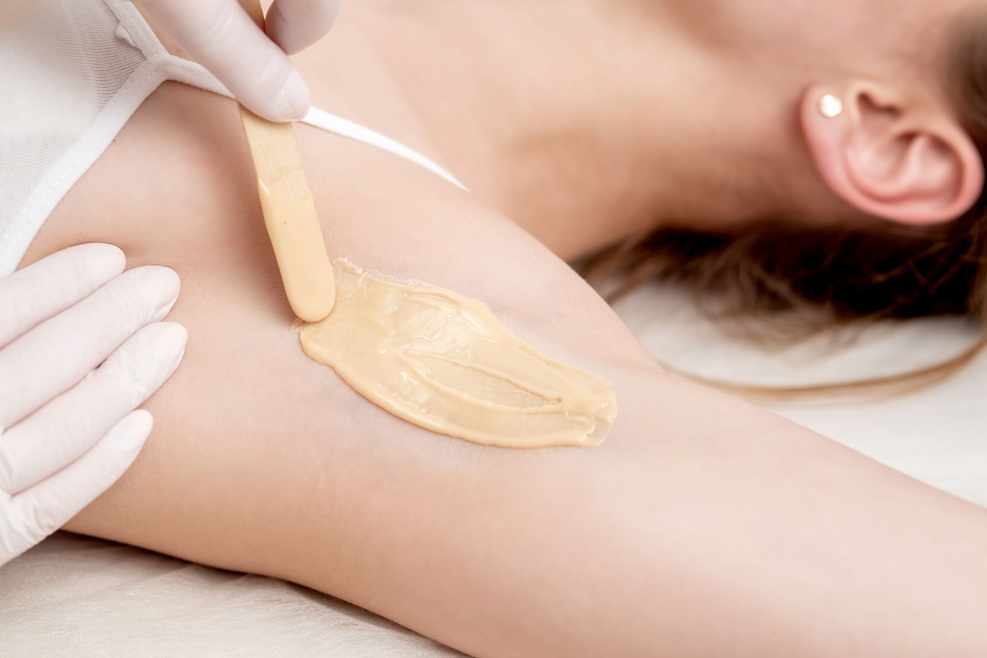 A woman is getting her armpit waxed in a beauty salon.