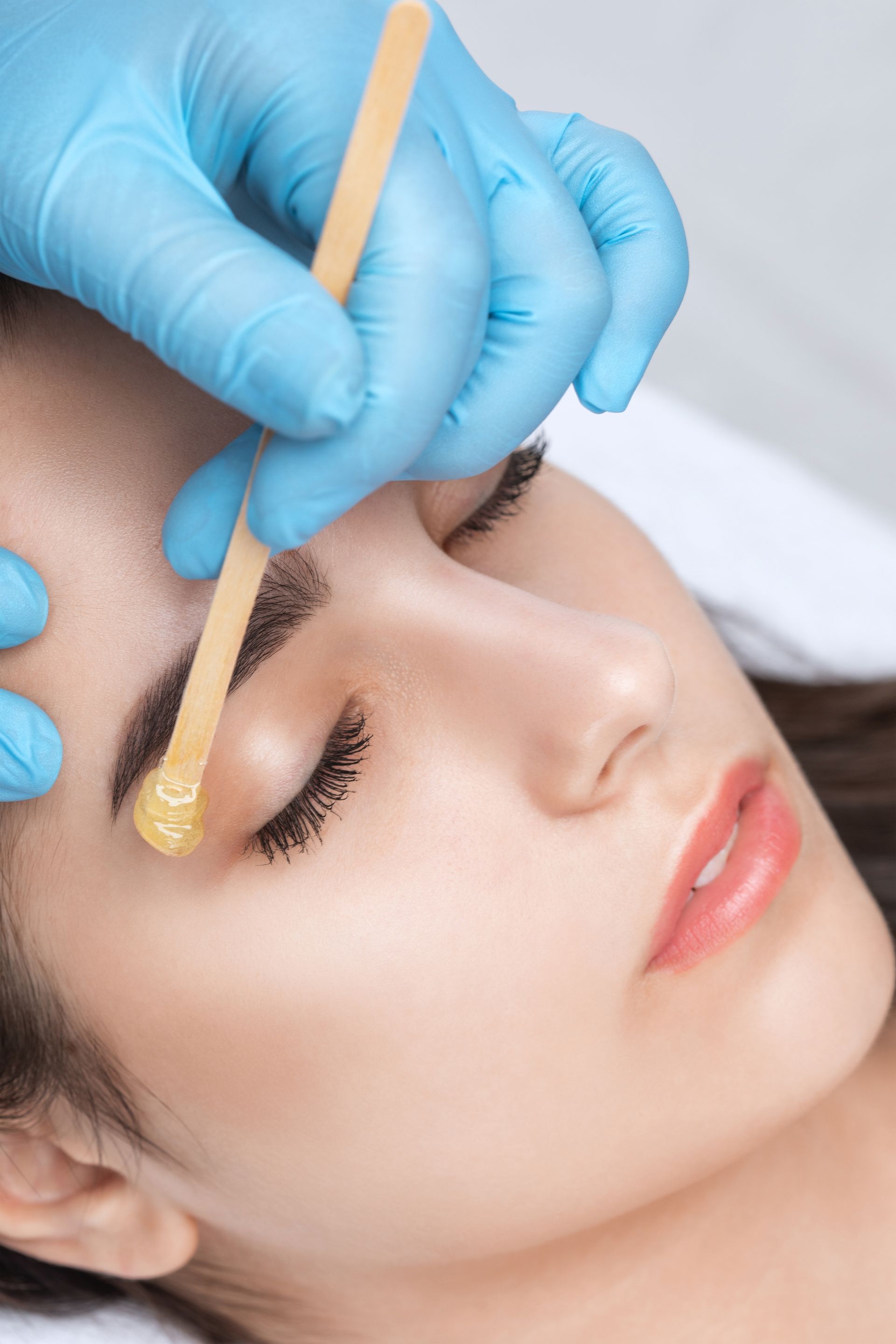 A woman is getting her eyebrows waxed in a beauty salon.