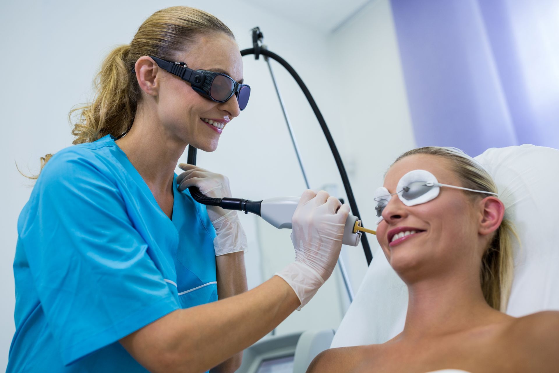 A woman is getting a laser hair removal treatment on her face.