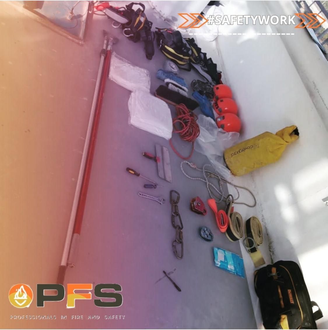 Un surtido de equipos y herramientas de seguridad, incluyendo botas, cascos y un bastón, se encuentra en el suelo. La escena es en un interior.