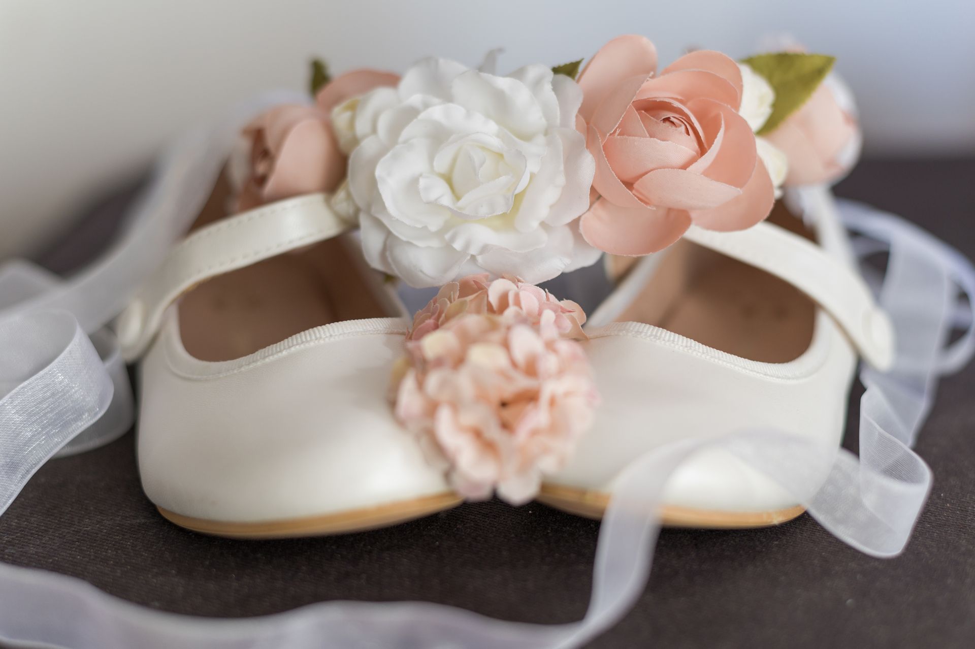 Un paio di scarpe bianche con dei fiori sono appoggiate su un tavolo.