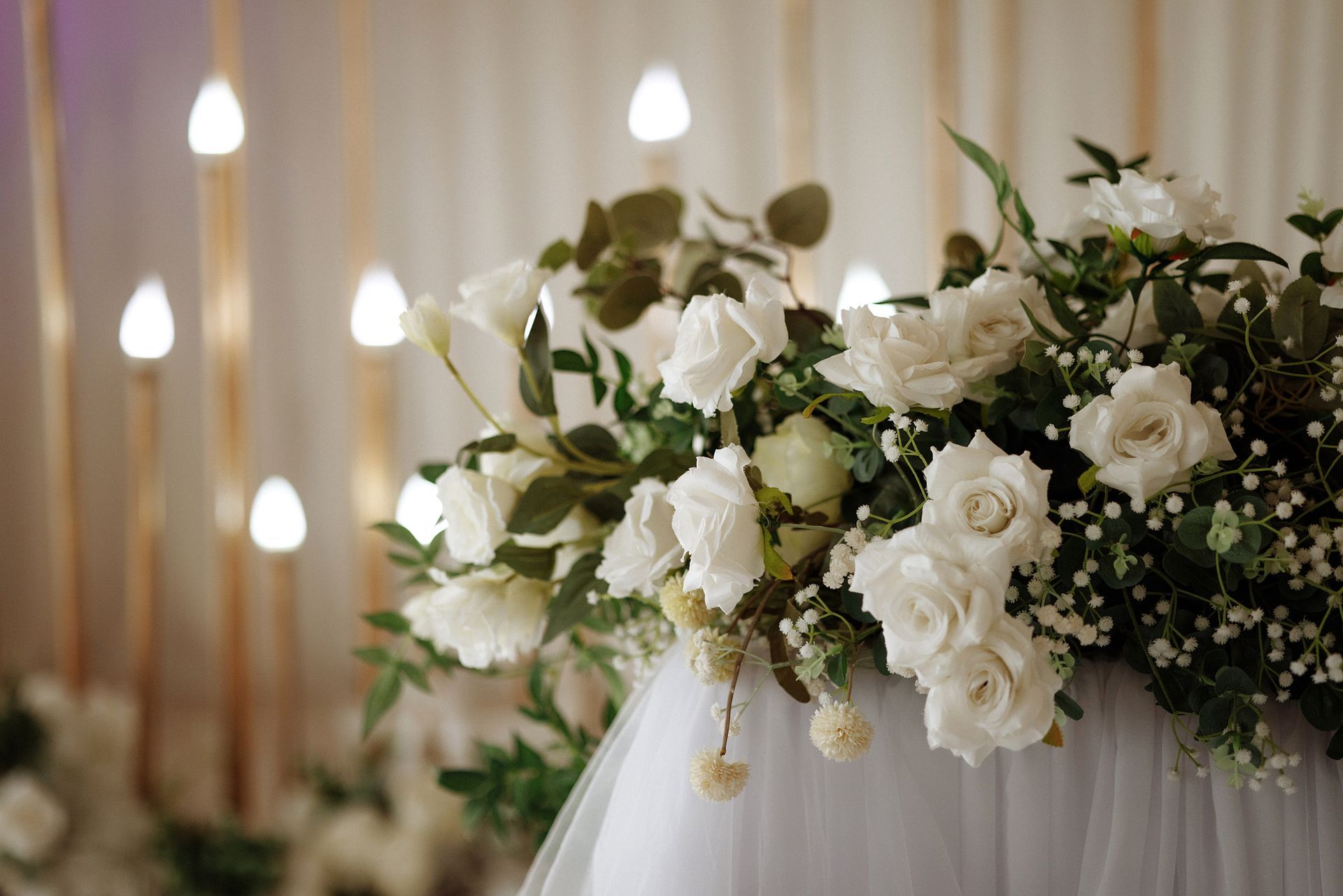 Un tavolo con fiori bianchi e candele sopra.