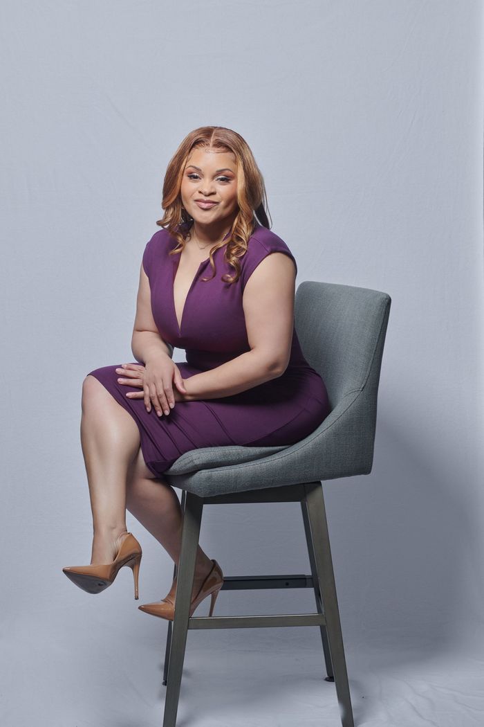 A woman in a purple dress is sitting on a chair.