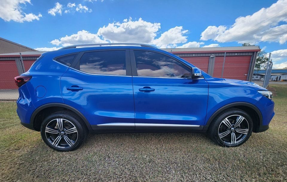 A Blue Car is Parked in a Gravel Lot in Front of a Building — Ace Tinting in Mareeba, QLD