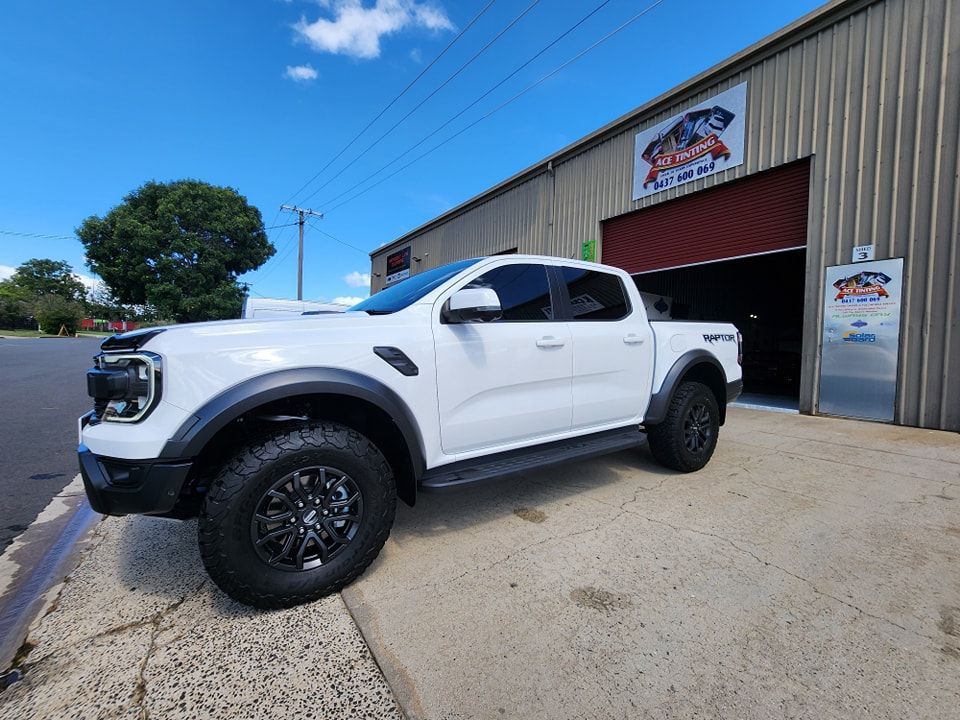 A White Truck is Parked in Front of a Building — Ace Tinting in Mareeba, QLD