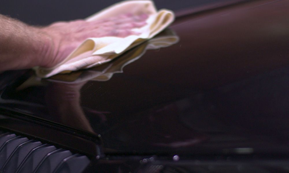 A Person is Cleaning a Car With a Cloth — Ace Tinting in Mareeba, QLD