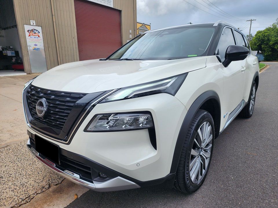 A white nissan rogue is parked on the side of the road in front of a building — Ace Tinting in Mareeba, QLD