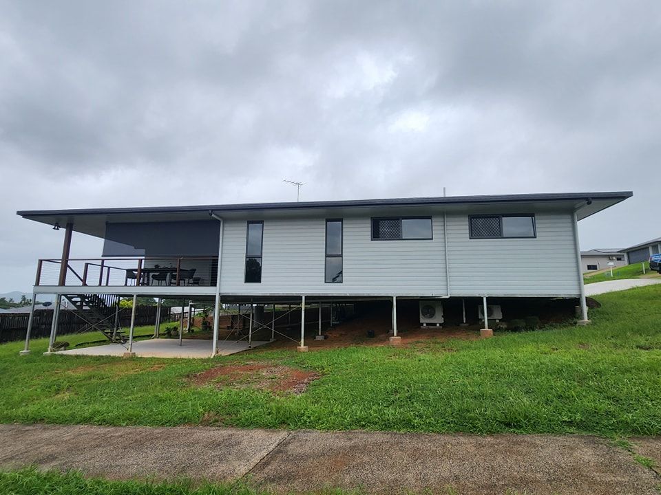 A white house is sitting on top of a grassy hill — Ace Tinting in Mareeba, QLD