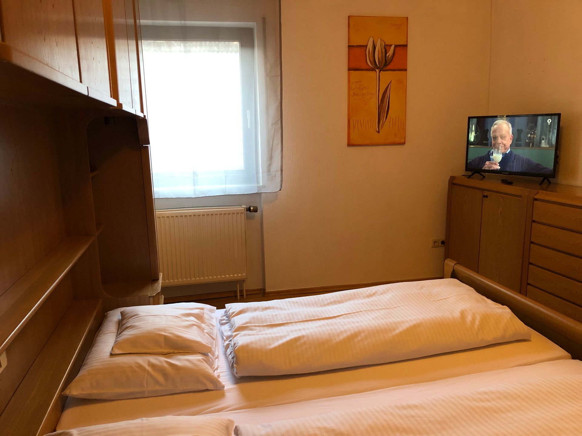 Ein Schlafzimmer mit einem Bett und einem Fernseher an der Wand.