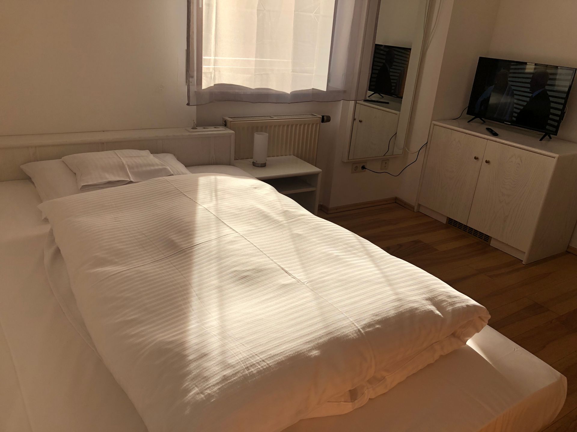 Ein Schlafzimmer mit Bett, Fernseher, Nachttisch und Spiegel.