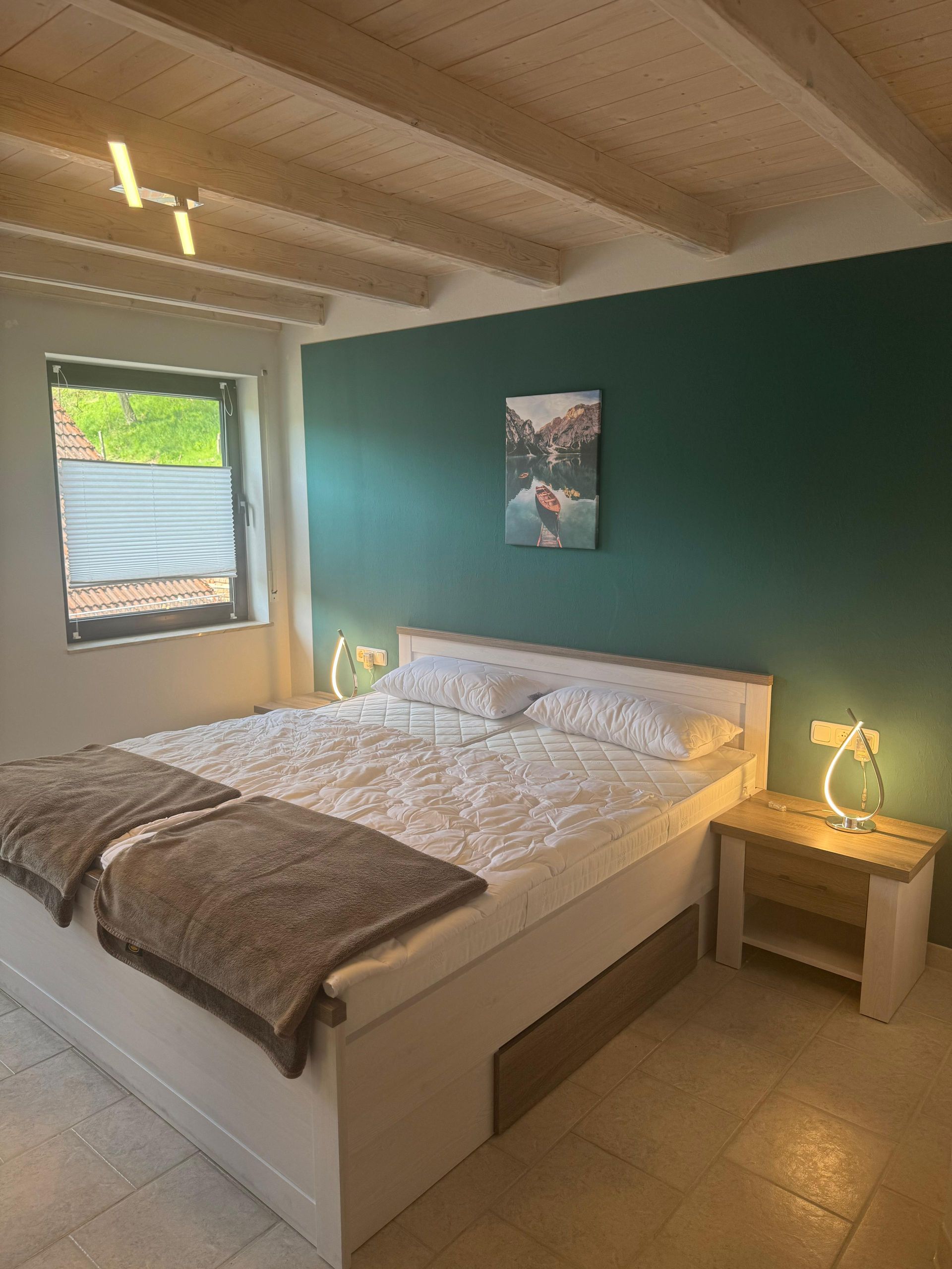 Ein Schlafzimmer mit einem Bett, einem Nachttisch, einer Lampe und einem Gemälde an der Wand.