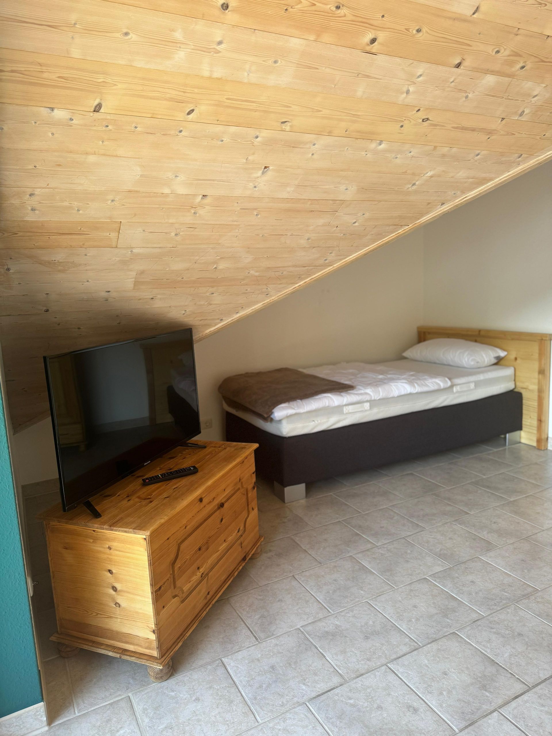 Ein Schlafzimmer mit Bett, Fernseher und Kommode.