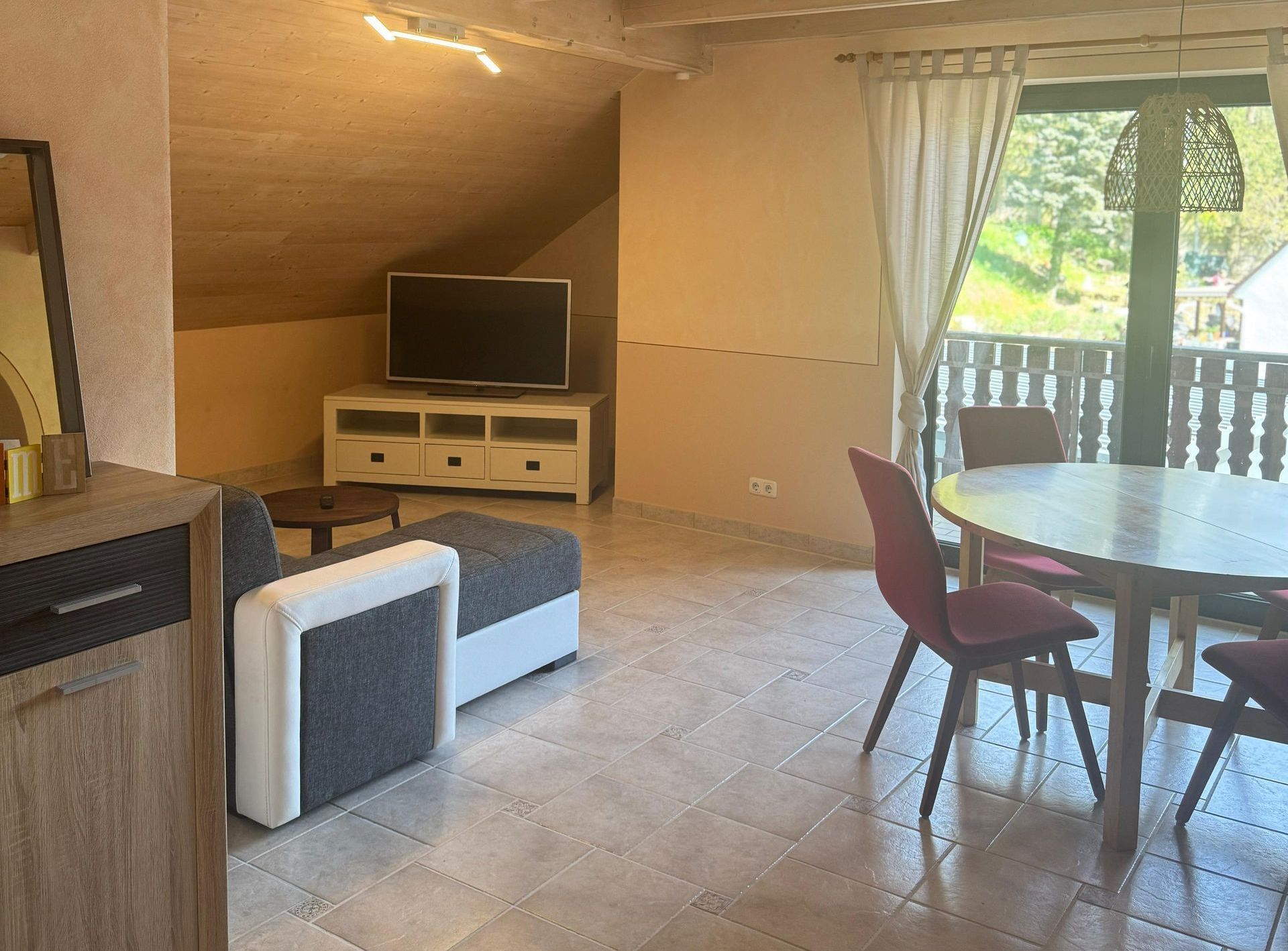 Ein Wohnzimmer mit Couch, Tisch, Stühlen und Flachbildfernseher.