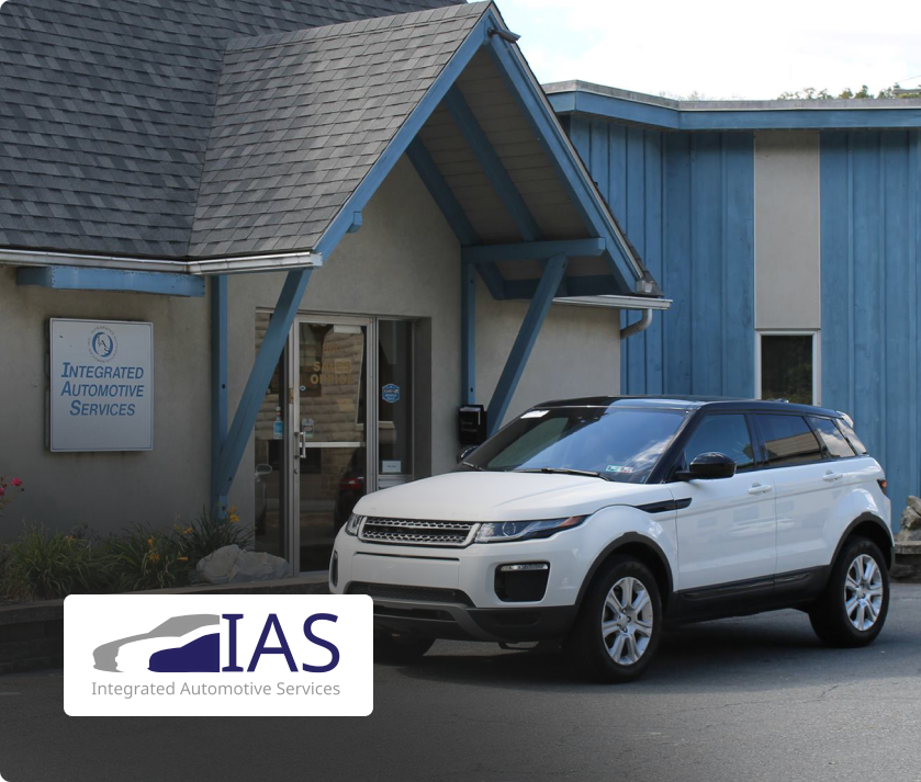 A white SUV and a dark gray sedan with their hoods open parked in front of an Ultimate Car Care auto shop.