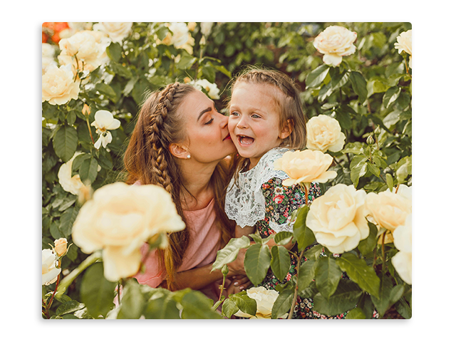 a woman is kissing her daughter on the cheek in a field of flowers .