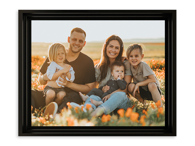 a framed picture of a family sitting in a field of flowers .