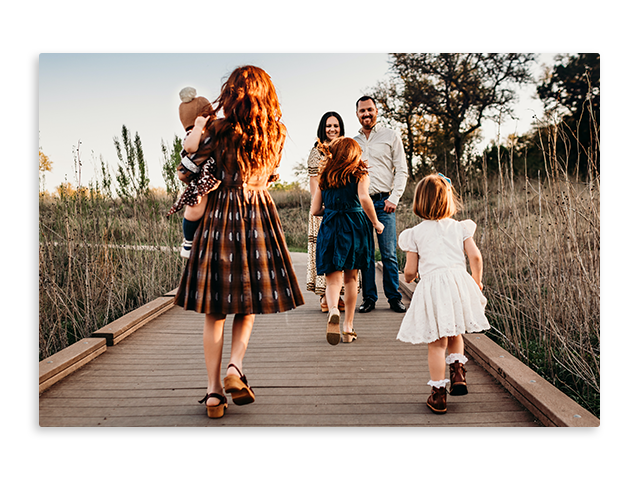 poster of a family is walking across a wooden bridge .
