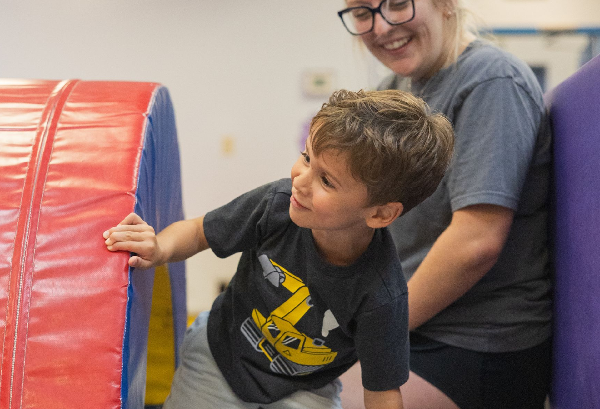 A little boy is sitting on a slide in front of a banner that says tumble bubble