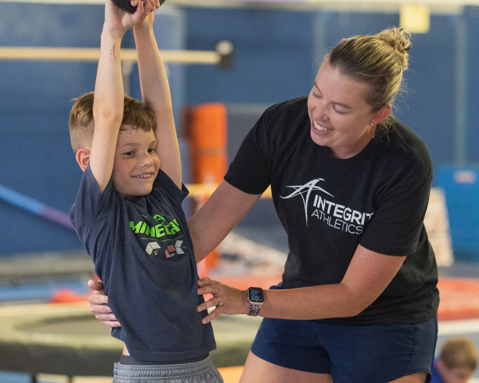 A man is helping a little girl do a handstand on the floor
