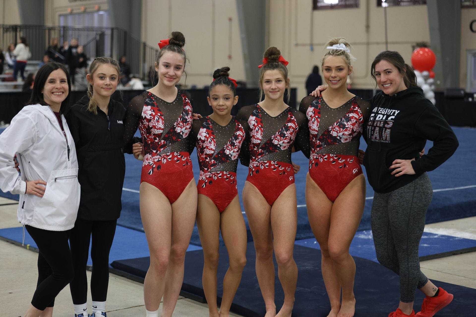 A group of female gymnasts are posing for a picture with their coaches.