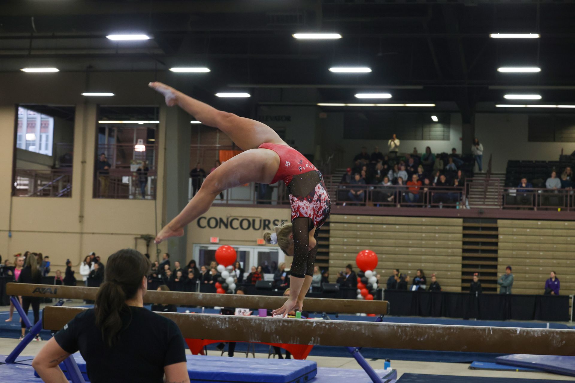 A gymnast is doing a handstand on a balance beam