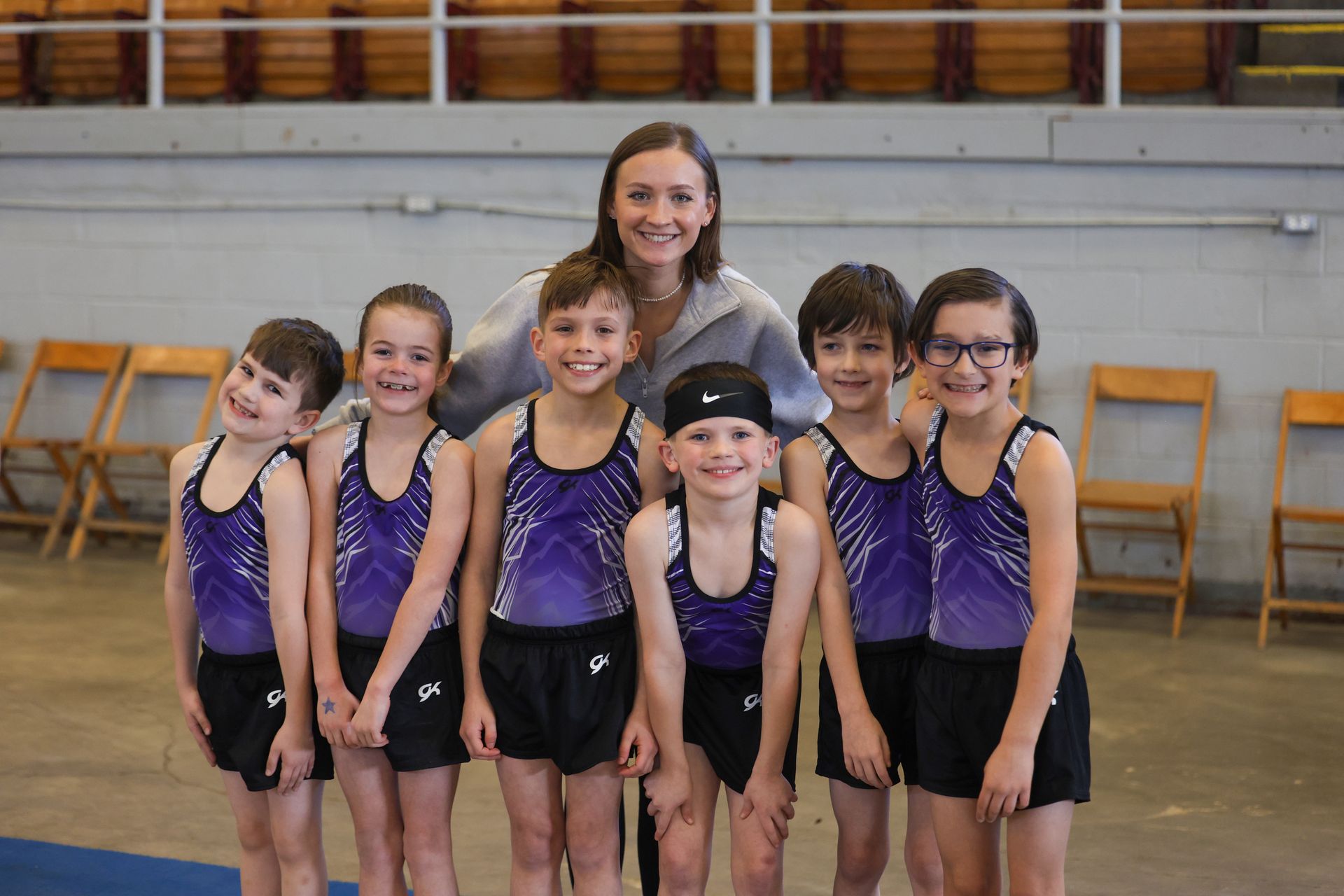 A group of young gymnasts are posing for a picture with their coach.
