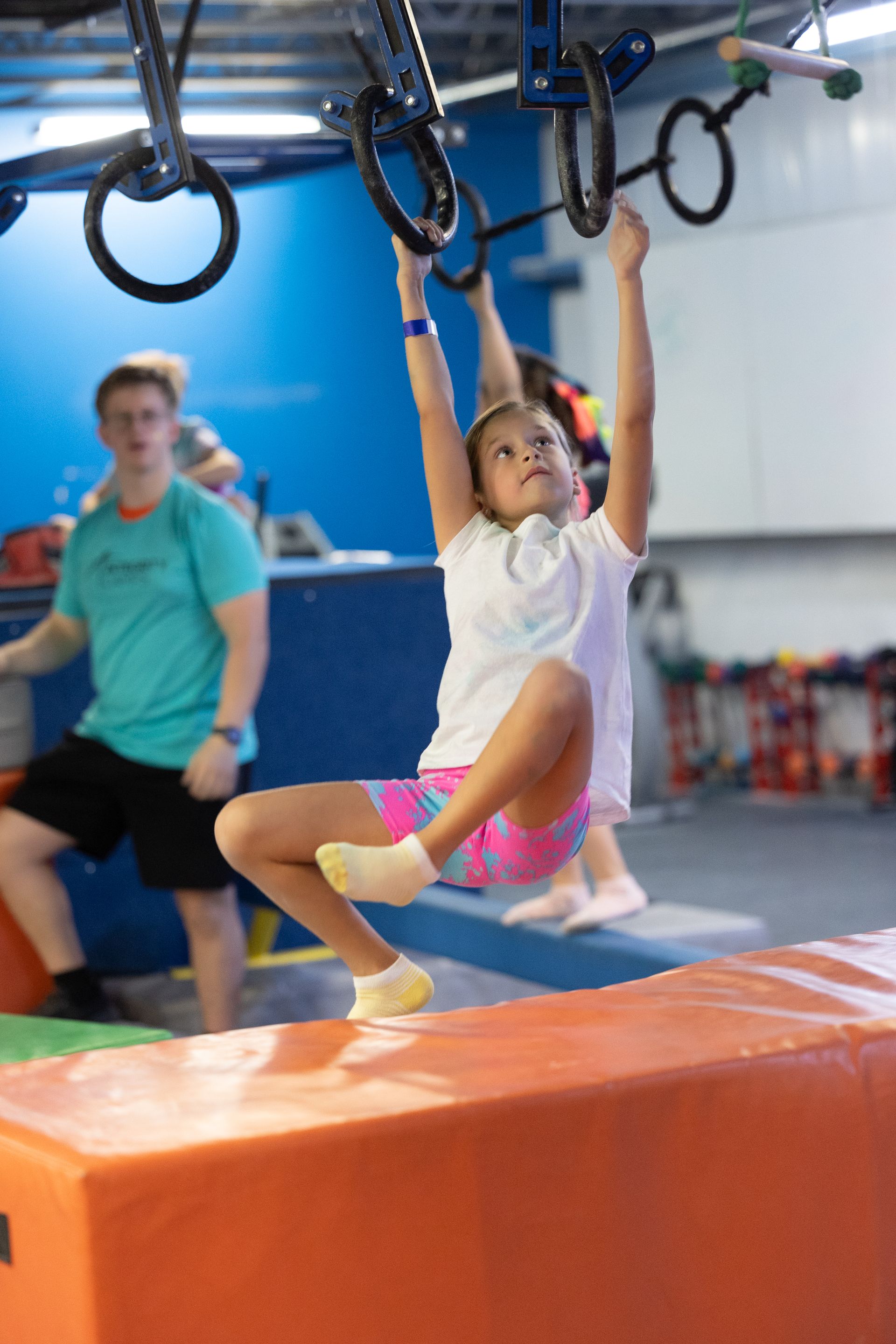 A little girl is sitting on the grass and smiling at the camera.