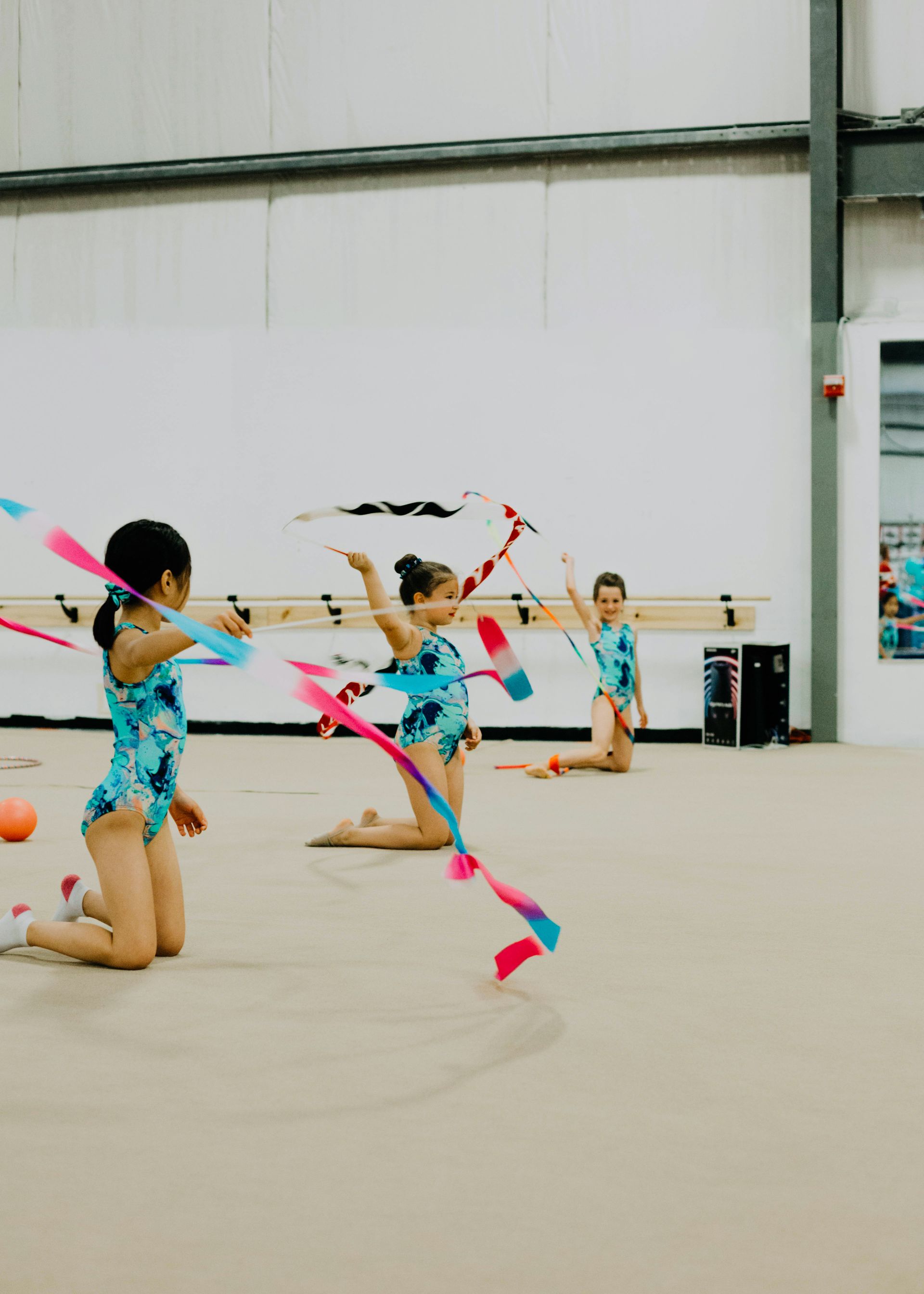 A group of young girls are doing rhythmic gymnastics with ribbons.